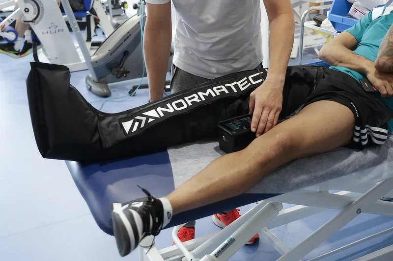 Physiotherapist applying compression therapy with a Normatec recovery system on a patient’s leg at Instituto Cugat’s Rehabilitation and Physiotherapy Unit.