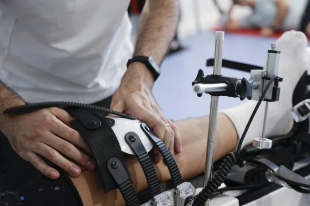 A physiotherapist placing a recovery device on a female athlete's knee during a rehabilitation session.